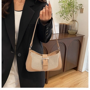 Detail of vintage beige canvas shoulder bag with brown leather trim and silver buckle