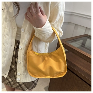 Detail of yellow nylon baguette bag featuring half-moon shape and durable zipper closure