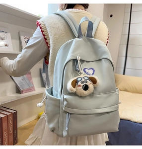 Detail of light blue nylon backpack with purple heart embroidery and plush dog charm