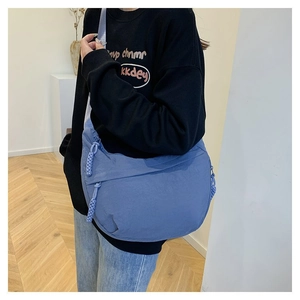 Détail du sac bandoulière bleu avec tirette tressée et tissu en nylon lisse et doux