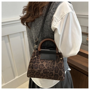 Détail du sac à main léopard avec poignées brunes et rivets dorés sur le côté