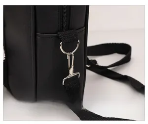 Detail of silver polished metal hook and thick woven shoulder strap on black leather bag