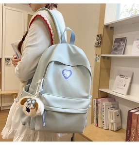 Detailed view of light blue nylon backpack with purple heart print and plush dog charm