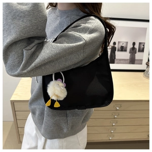 Detail shot of a black nylon crescent underarm bag with a cute white duck plush charm