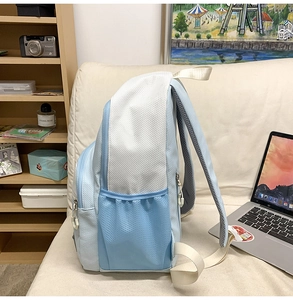 Close-up of a blue and white nylon backpack showing side mesh pocket and durable straps