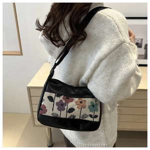 Close-up of stylish retro floral tapestry shoulder bag with adjustable black leather strap