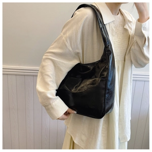 Close-up of a black glossy leather hobo bag showing texture and elegant shoulder fit