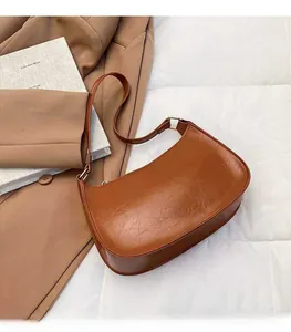 Macro detail of retro brown leather shoulder bag with glossy oil wax finish and metal buckle
