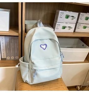 Detail of mint green canvas backpack featuring a purple graffiti heart and drawstring pockets