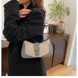 Close-up of beige canvas underarm bag with grey leather trim and silver metal buckle