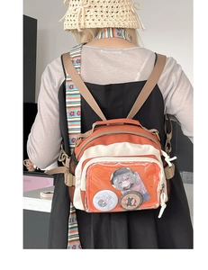 Détail du sac à dos bicolore orange avec poche PVC transparente et badges de style anime