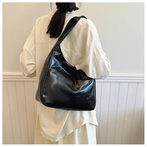 Detail shot of the glossy black Hobo bag with a spacious design and wide shoulder strap