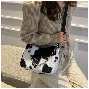 Detail of plush cow print tote bag with silver chain and black faux leather strap