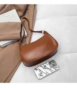 Close-up of caramel brown leather hobo bag with vintage texture and metal buckle