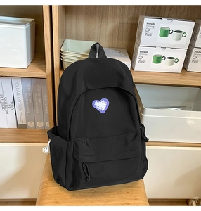Detail view of black canvas backpack featuring purple heart patch and side water bottle pocket