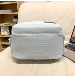 Detail of light blue nylon backpack with honeycomb texture on a beige fabric sofa
