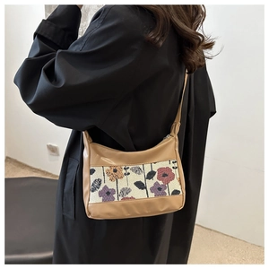 Detail view of khaki PU and canvas shoulder bag with floral print on a black coat model