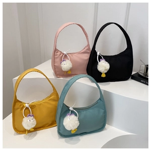 Close-up of four nylon crescent handbags in pastel colors with cute monster plush charms