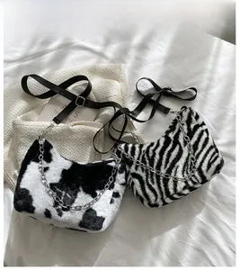 Detailed view of fuzzy plush tote bags in cow and zebra prints with metal chains