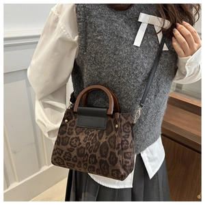 Gros plan sur un sac léopard avec poignée en bois vintage et tenue en tricot gris chic