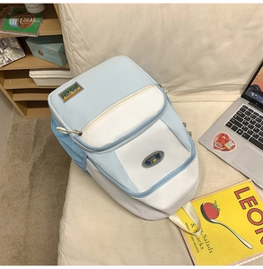 Detail view of a light blue nylon backpack with laptop and books in a modern scene