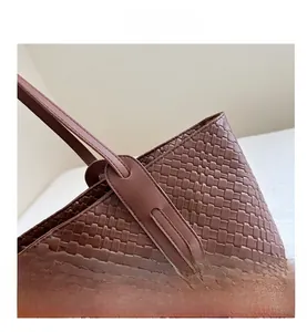 Detail of brown woven faux leather tote bag showing textured square pattern and stitching