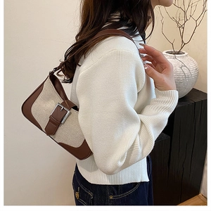 Detail view of vintage canvas underarm bag with brown leather trim and silver buckle strap