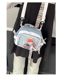 Détail du sac ita bleu avec fenêtre transparente, badges et bandoulière rayée colorée
