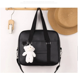 Detail of black Japanese JK uniform bag with white plush bear charm and adjustable strap