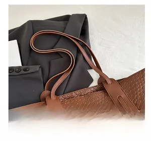 Close-up of brown faux leather tote bag with woven texture and crocodile pattern