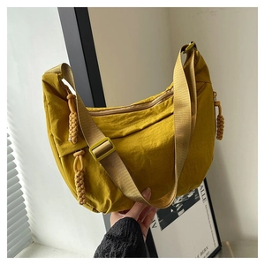 Détail du sac hobo jaune en nylon avec bandoulière réglable et nœud de fermeture éclair