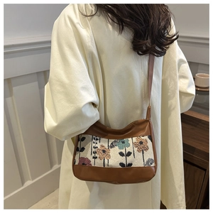 Side view of floral embroidery canvas shoulder bag on a trench coat model