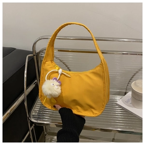 Detail of bright yellow nylon crescent bag with cute white plush monster charm