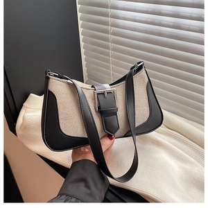 Detailed shot of beige canvas underarm bag with black leather trim and silver metal buckle