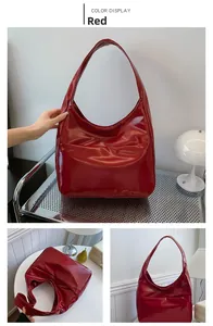 Detail view of large red patent leather hobo bag with wide shoulder strap and glossy finish