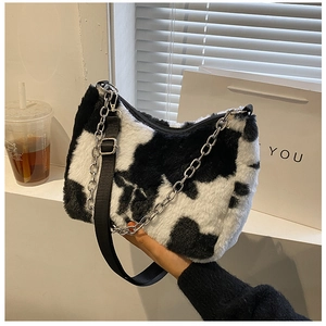Detail of cow print plush tote bag with adjustable strap and metal chain detail