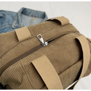 Detail of khaki corduroy tote bag showing metal zipper closure and nylon webbing strap