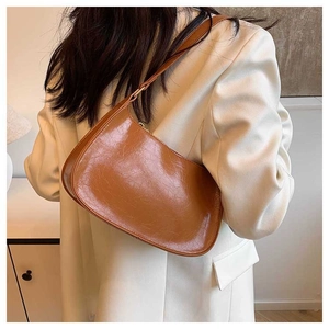 Detail of caramel faux leather bag with vintage texture on a model wearing white blazer