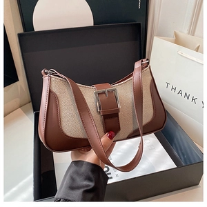 Detail of vintage canvas and brown leather baguette bag inside a premium gift box