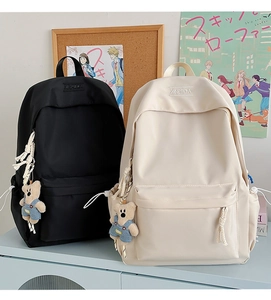 Detailed view of durable nylon backpack showing drawstring side pockets and cute bear charm