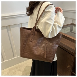Close-up of the intricate woven texture and fine stitching on the brown tote bag