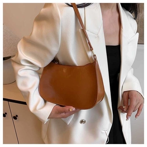 Close-up of a brown matte PU leather crescent bag with a zipper and fine leather strap