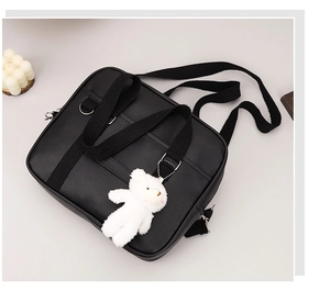 Detail of black Japanese style crossbody bag with a cute white plush bear keychain accessory
