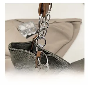 Vue détaillée du sac cabas en toile grise avec anneaux métalliques et joints en cuir
