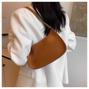 Brown faux leather crescent underarm bag shown on model with white blazer