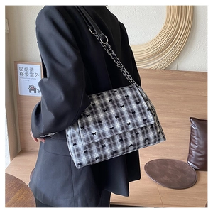 Détail du sac cabas à carreaux noir et blanc avec nœuds brodés et bandoulière chaîne