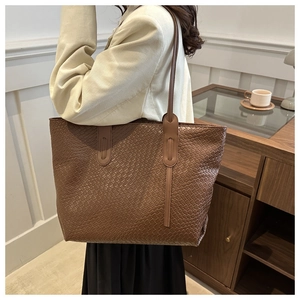 Detailed close-up of dark brown woven tote bag showcasing leather texture and shoulder strap