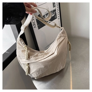 Détail du sac croissant en nylon plissé beige avec fermeture éclair à nœud tissé