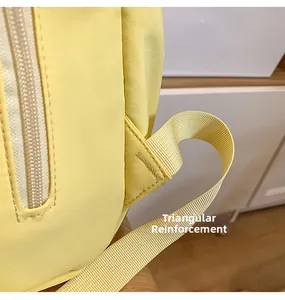 Detail of reinforced triangle stitching and white zipper on yellow nylon school backpack