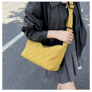 Detailed close-up of yellow quilted nylon tote bag with geometric triangular patterns